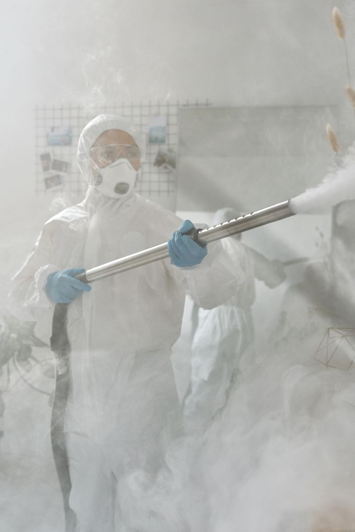 A person wearing full protective equipment is fumigating a room to make sure it is sterilized against viruses.